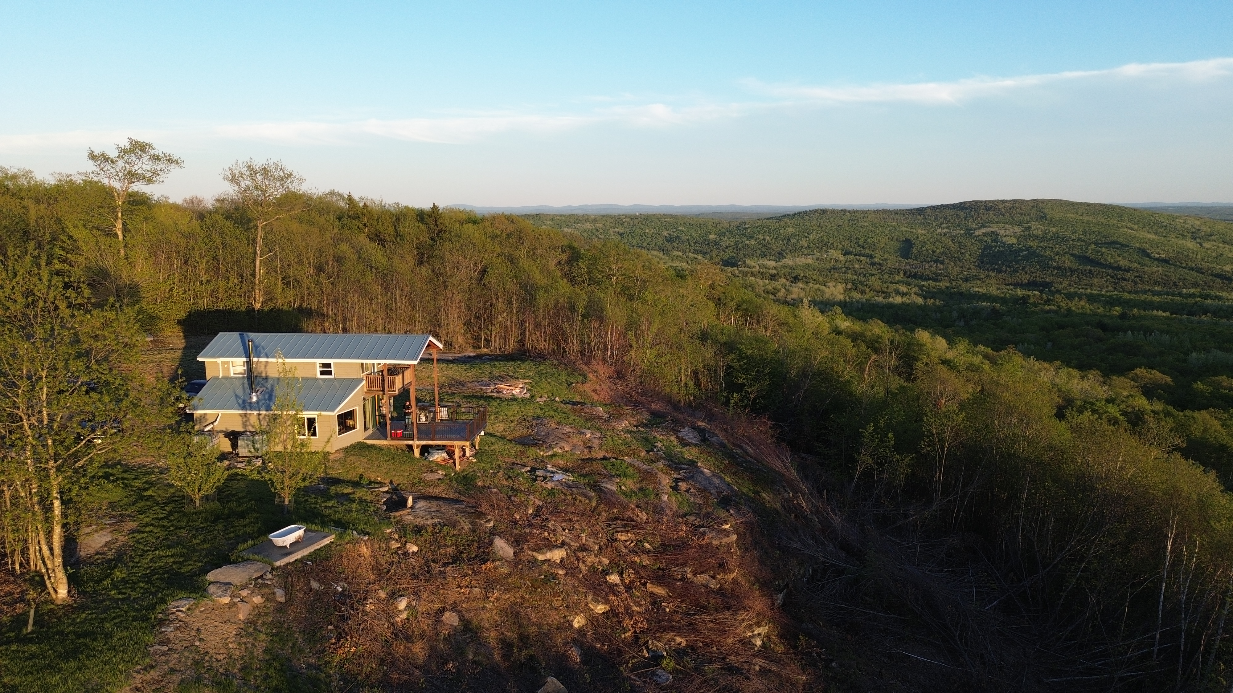 The home on its ridge, looking out over rolling forest toward the horizon